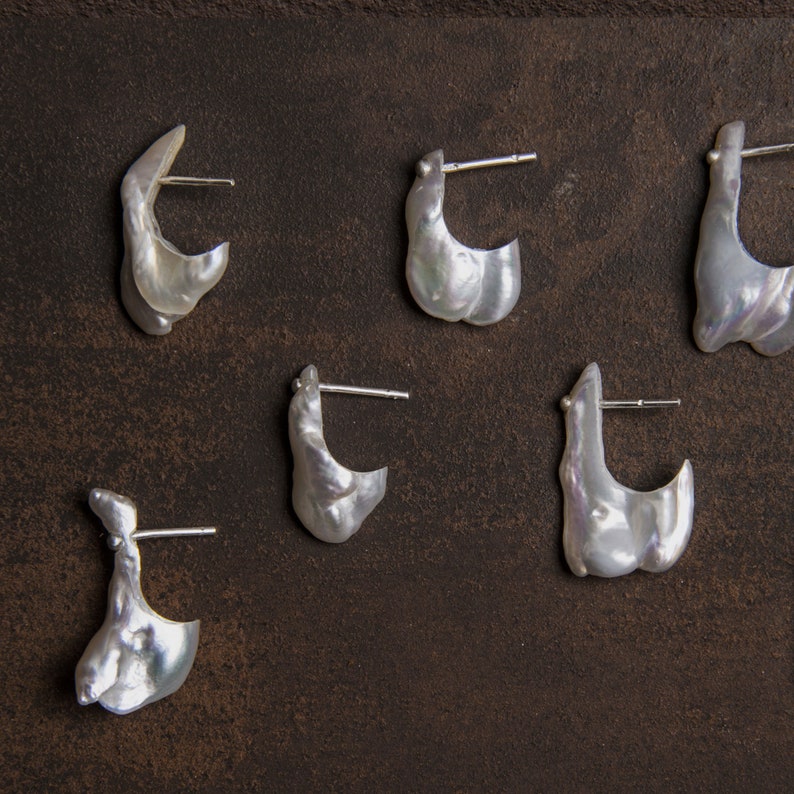 May include: Five pairs of white pearl earrings with silver posts. The earrings are all different shapes and sizes.