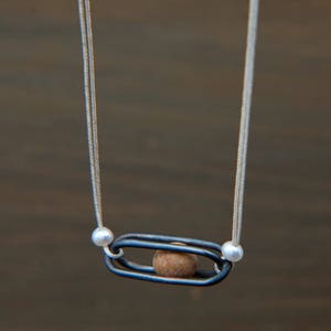 Pebble in Cage by Ariadni Kypri, tiny pebble, silver charm necklace_ YDOR collection