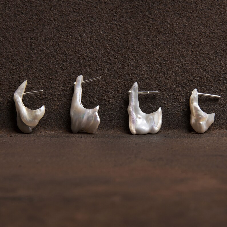 May include: Four white pearl earrings with silver posts. The earrings are shaped like irregular, organic forms.