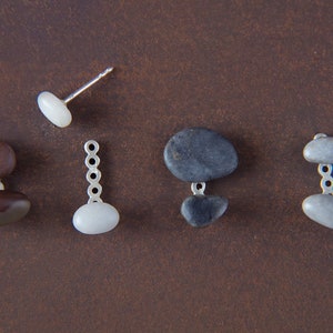 May include: Five pairs of earrings featuring different colored stones and metal accents. The earrings are displayed on a brown surface.