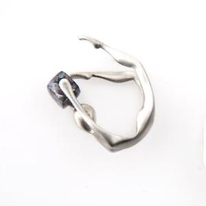 Könnte beinhalten: Ein silberner Ring mit geometrischem Design, der mit einem schwarzen Stein verziert ist. Der Ring ist in Form einer Person geformt, die einen Handstand macht.