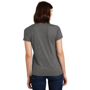 Puede incluir: Una camiseta gris jaspeada con cuello en V. La camiseta de manga corta se combina con vaqueros azules. El modelo se ve desde atr&aacute;s, mostrando la espalda de la camiseta y el corte de la prenda.