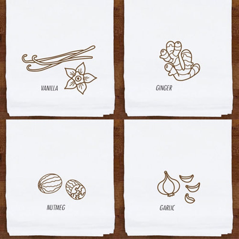 May include: Four white kitchen towels with brown line drawings of spices. The towels feature illustrations of vanilla, ginger, nutmeg, and garlic. Each towel has the name of the spice printed below the illustration.