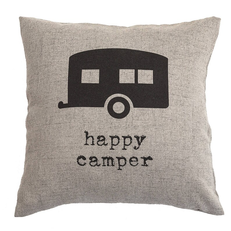 May include: A square, gray decorative pillow with a black camper graphic and the words "happy camper" printed below. The pillow has a textured appearance, suitable for home decor.