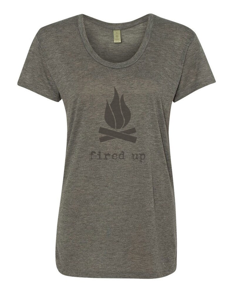 Puede incluir: Camiseta gris jaspeado con cuello redondo y un gr&aacute;fico gris oscuro de una fogata y las palabras "fired up" impresas debajo. La camiseta tiene mangas cortas y un corte holgado.