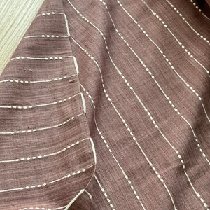 May include: A close-up of a brown fabric with white vertical stripes. The stripes are made of small white dots.
