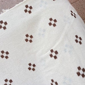 May include: White fabric with a repeating pattern of brown checkered squares.