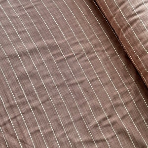 May include: Brown fabric with white vertical stripes and small white dots. The fabric has a subtle texture.