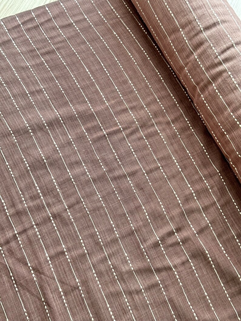 May include: Brown fabric with white vertical stripes and small white dots. The fabric has a subtle texture.