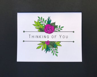 Könnte beinhalten: Eine weiße Karte mit schwarzem Rand und dem Text "Thinking of You" in schwarzen Buchstaben. Die Karte ist mit einer rosa Rose und grünen Blättern verziert.