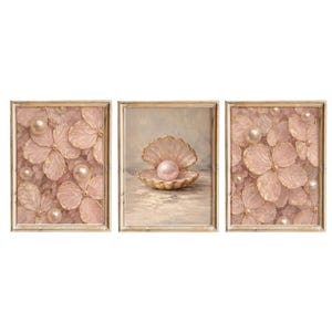 May include: A triptych of framed art prints. Two prints feature pink floral designs with gold accents and pearls. The central print showcases a pearl within an open seashell. The frames have a gold finish, creating a cohesive set.