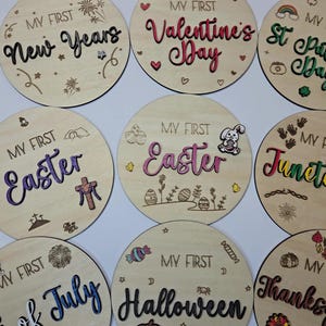 May include: Set of ten round wooden ornaments with various holiday themes. Each ornament features a different holiday, including New Years, Valentine's Day, St. Patrick's Day, Easter, Juneteenth, 4th of July, Halloween, Thanksgiving, and Christmas. The ornaments are decorated with festive colors and designs.
