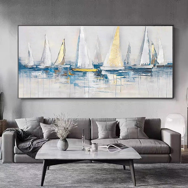 May include: Abstract painting of sailboats on a blue and white water background. The sailboats are white with gold accents. The painting is framed in a black frame.