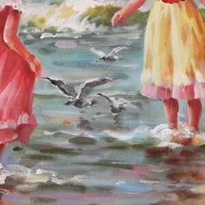 May include: Two girls in dresses stand on a beach with their feet in the water. The girl on the left is wearing a pink dress with white lace trim. The girl on the right is wearing a yellow dress with pink lace trim. There are seagulls flying overhead.