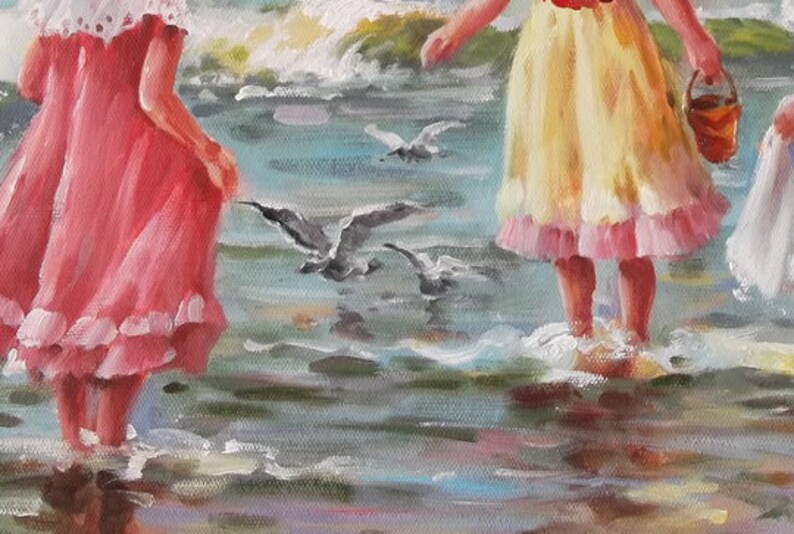 May include: Two girls in dresses stand on a beach with their feet in the water. The girl on the left is wearing a pink dress with white lace trim. The girl on the right is wearing a yellow dress with pink lace trim. There are seagulls flying overhead.
