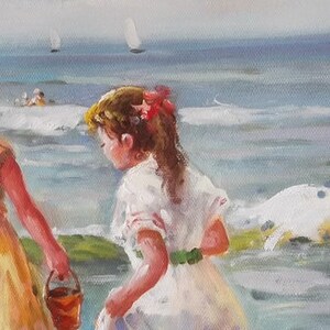 May include: Two girls in summer dresses play on a beach. One girl wears a yellow dress with a red belt and holds a bucket. The other girl wears a white dress with a green sash. The ocean is in the background.