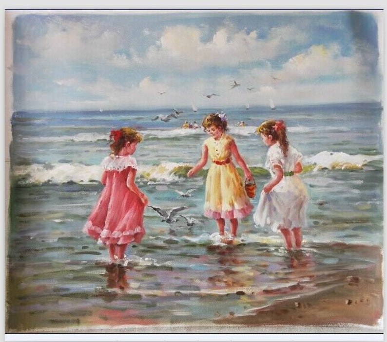 May include: Three girls in dresses play on a beach with seagulls. The girl in the pink dress is on the left, the girl in the yellow dress is in the center, and the girl in the white dress is on the right. The girls are standing in the shallow water of the ocean.