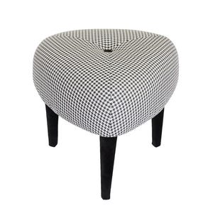 May include: A heart-shaped ottoman with a black and white houndstooth pattern. The upholstered top is supported by three black, tapered legs. The design features a button detail in the center of the ottoman.