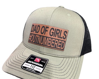 Dad of Girls OUTNUMBERED Leatherette Patch Hat is a Richardson 112 Trucker Hat with adjustable snapback.