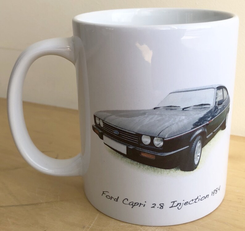 Pu&ograve; includere: Tazza in ceramica bianca con un Ford Capri 2.8 Injection 1984 nero stampato su di essa.