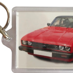 May include: A red Ford Capri keychain with a black roof and a silver key ring.