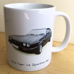 Pu&ograve; includere: Tazza in ceramica bianca con un'illustrazione di una Ford Capri 2.8 Injection 1984 nera e verde.