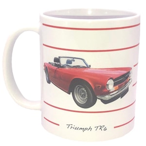 May include: White ceramic mug with a red Triumph TR6 convertible car illustration. The car has a black interior and silver wheels. Red horizontal stripes encircle the mug, with the text "Triumph TR6" at the bottom.
