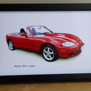 May include: A framed print of a red Mazda MX-5 convertible car. The car is on a white background and the text "Mazda MX-5 2003" is printed below the car.