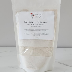 Könnte beinhalten: Ein klarer Beutel mit Oatmeal + Coconut Milk Bath Soak mit Calendula. Das Etikett lautet "Poppy Lane Organics". Das Produkt enthält 227 g Badesalz. Das Etikett listet Zutaten und Gebrauchsanweisung auf. Der Beutel ist versiegelt.