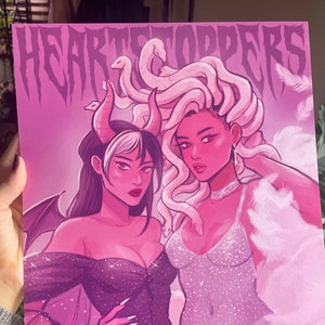 May include: A pink and purple illustration of two women, one with a snake-like hairdo and the other with horns and a bat wing. The text "HEARTSTOPPERS" is at the top of the image.