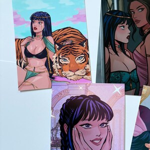 以下が含まれることがあります： 女性のイラストが描かれたアートプリントのコレクション。1つのプリントは虎と女性、別のプリントは2人の女性、3つ目は顔に手を当てた女性が描かれています。アートスタイルは漫画を彷彿とさせます。