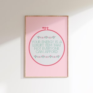 Puede incluir: Un estampado rosa enmarcado con un diseño de punto de cruz. El diseño presenta un aro de bordado circular con el texto "YOUR ENERGY IS A LUXURY ITEM THAT NOT EVERYONE CAN AFFORD" en verde y blanco.