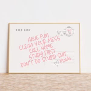 Könnte beinhalten: Eine gerahmte Postkarte mit den Worten "POST CARD" oben. Rosa Text lautet "HAVE FUN CLEAN YOUR MESS CALL HOME STUDY FIRST DON'T DO STUPID SHIT Mom" mit einem Herz und einer Briefmarkengrafik.