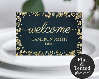 Puede incluir: Un cartel de bienvenida azul oscuro con detalles de purpurina dorada y un diseño floral. El cartel dice "welcome" en escritura dorada y "Cameron Smith -Table 1-" en letras doradas. El cartel está etiquetado como "Flat & Tented place card".