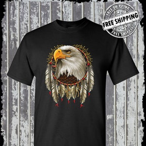 May include: Black t-shirt with a graphic of a bald eagle inside a dreamcatcher with feathers. The text "Kinsman Trading Co. LLC" is at the bottom of the shirt.