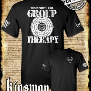 May include: Black t-shirt with white text that reads "This is what I call group therapy" and a target with bullet holes. The back of the shirt has a white circle with the text "1776" and stars around it.