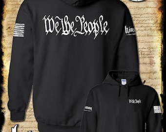 May include: Black hooded sweatshirt with the phrase "We the People" printed in white on the back. The left sleeve has a small American flag design and the right sleeve has the word "Kinsman" printed in white.