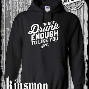 May include: Black hooded sweatshirt with the text "I'M NOT Drunk ENOUGH TO LIKE YOU yet." in white. The sweatshirt has a front pocket and a drawstring hood. The brand name "Kinsman trading co. llc" is printed at the bottom.