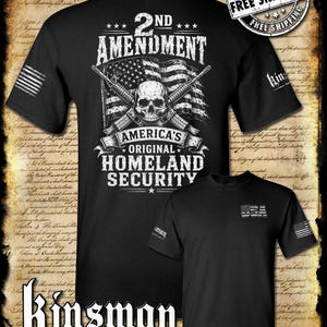 May include: A black short-sleeve t-shirt featuring a graphic of a skull, two crossed rifles, and an American flag with the text 2nd Amendment America's Original Homeland Security. A smaller version shows the text USA on the chest.