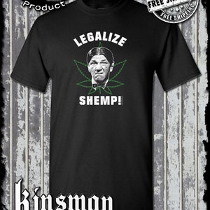 Könnte beinhalten: Schwarzes T-Shirt mit einem grünen Marihuana-Blatt und einem Bild von Shemp Howard von den Three Stooges. Der Text "Legalize Shemp!" ist auf dem T-Shirt aufgedruckt.