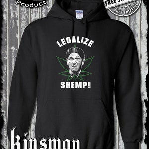Könnte beinhalten: Schwarzer Kapuzenpullover mit einer Grafik von Shemp Howard von den Three Stooges in einem grünen Cannabisblatt, mit den Worten "LEGALIZE SHEMP!". Der Pullover hat auch den Text "Offical Licensed Product" und "Kinsman trading co llc".
