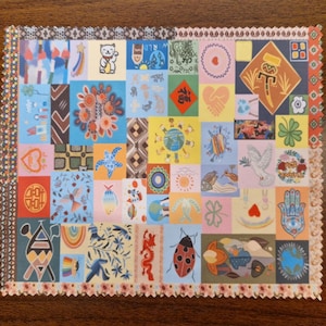 May include: A square fabric cloth featuring a patchwork design of numerous small, colorful illustrations including a lucky cat, a dove, a ladybug, a hamsa hand, a dragon, and various floral and geometric patterns, finished with a decorative pinked edge.