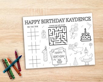 May include: A black and white birthday activity sheet with the text "HAPPY BIRTHDAY KAYDENCE". The sheet includes a tic-tac-toe grid, a maze, and illustrations of ducks, a cake, and party items. Crayons are visible on the left.