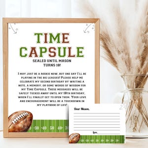 Puede incluir: Una impresión enmarcada con las palabras "TIME CAPSULE" en verde y marrón, sellada hasta que Mason cumpla 18 años. Incluye un gráfico de fútbol y una pequeña tarjeta con líneas para escribir. Un jarrón con flores secas está en el fondo.