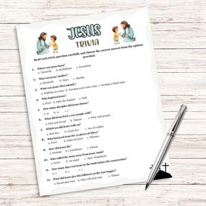 Pu&ograve; includere: Un foglio di gioco a quiz stampato intitolato "Jesus Trivia" con domande sulla vita di Ges&ugrave;. Il foglio include illustrazioni di Ges&ugrave; e di un bambino. Una penna d'argento poggia sulla superficie di legno.