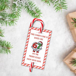 May include: A red and white candy cane tag with text that reads "This candy cane is rated like 67 on the merry scale! From: Your Name". The tag is decorated with a red and white striped border and a candy cane.