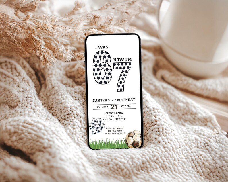 May include: A smartphone displays a soccer-themed birthday invitation. The black and white design features the text "I WAS 6, NOW I'M 7" with soccer ball graphics. The invitation includes event details like date, time, and location.