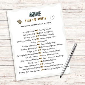 Pu&ograve; includere: Un foglio di carta bianco con il titolo "BIBLE THIS OR THAT?" e un elenco di domande sullo studio della Bibbia. Una penna d'argento &egrave; appoggiata sulla superficie di legno accanto alla carta.