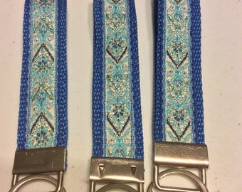May include: Three blue and white patterned keychains with silver key rings. The keychains have a blue background with a white and gold patterned stripe.