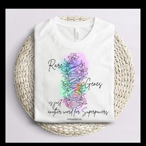 May include: White t-shirt with a rainbow-coloured DNA strand design and the text "Rare Genes is just another word for Superpowers" with the website curemapk31p3.org at the bottom.